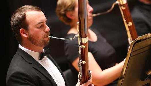 a man plays the bassoon in an orchestra