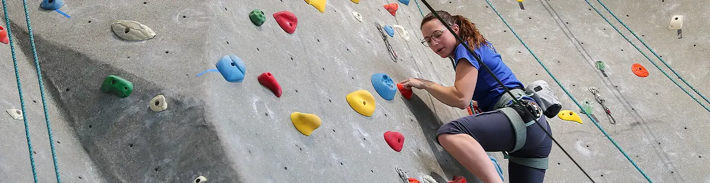Student climbing rock wall