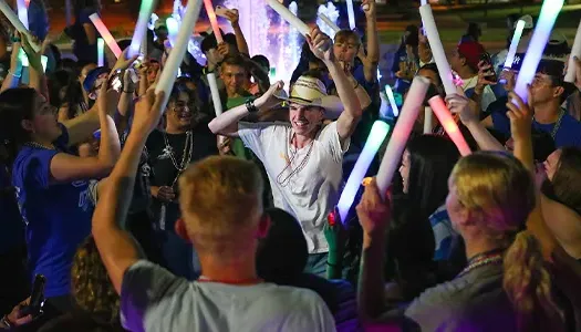 students wave glow sticks and dance at a concert